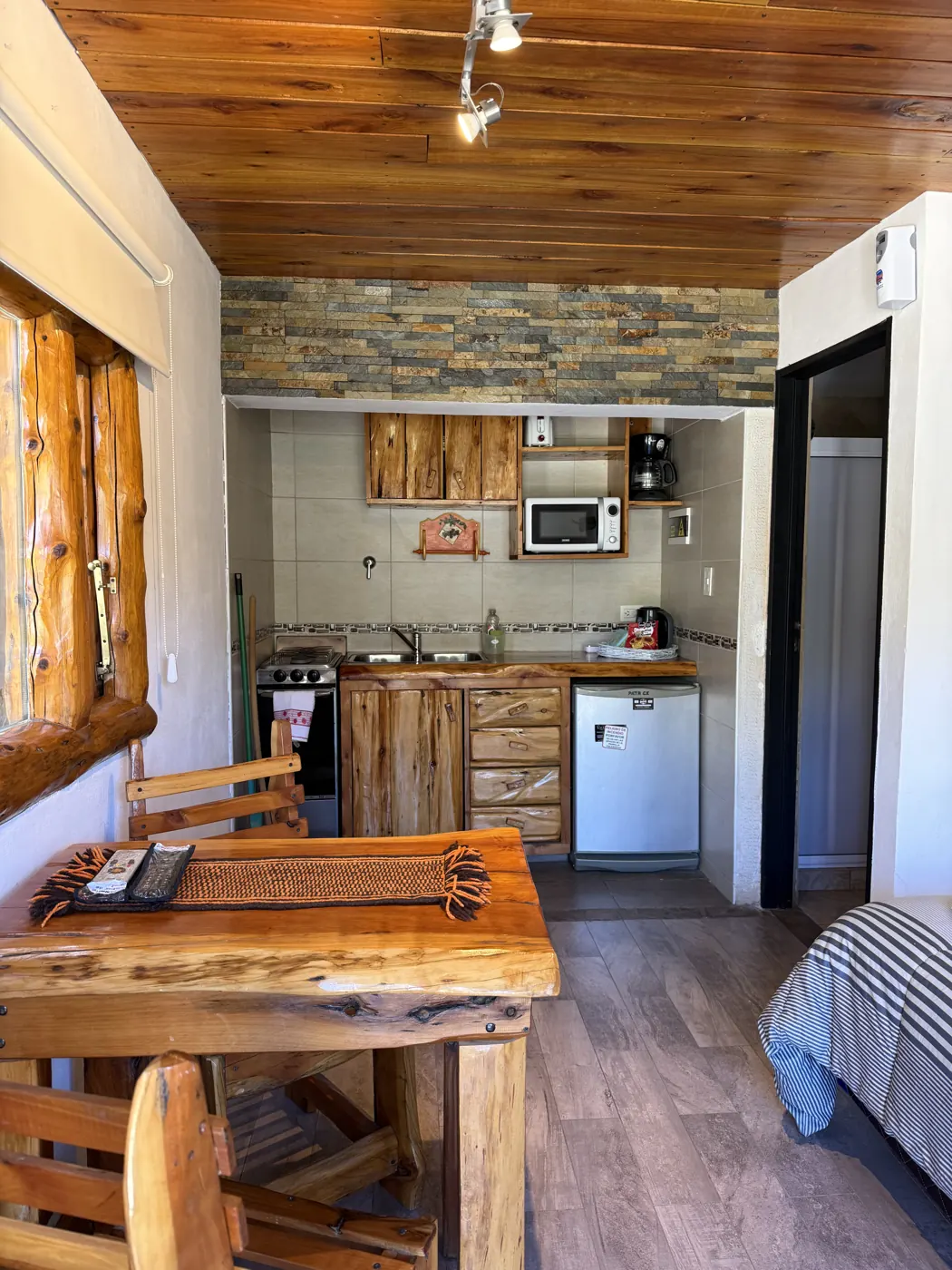 Ambiente integrado de la cabaña Amulen con cama, cocina y comedor