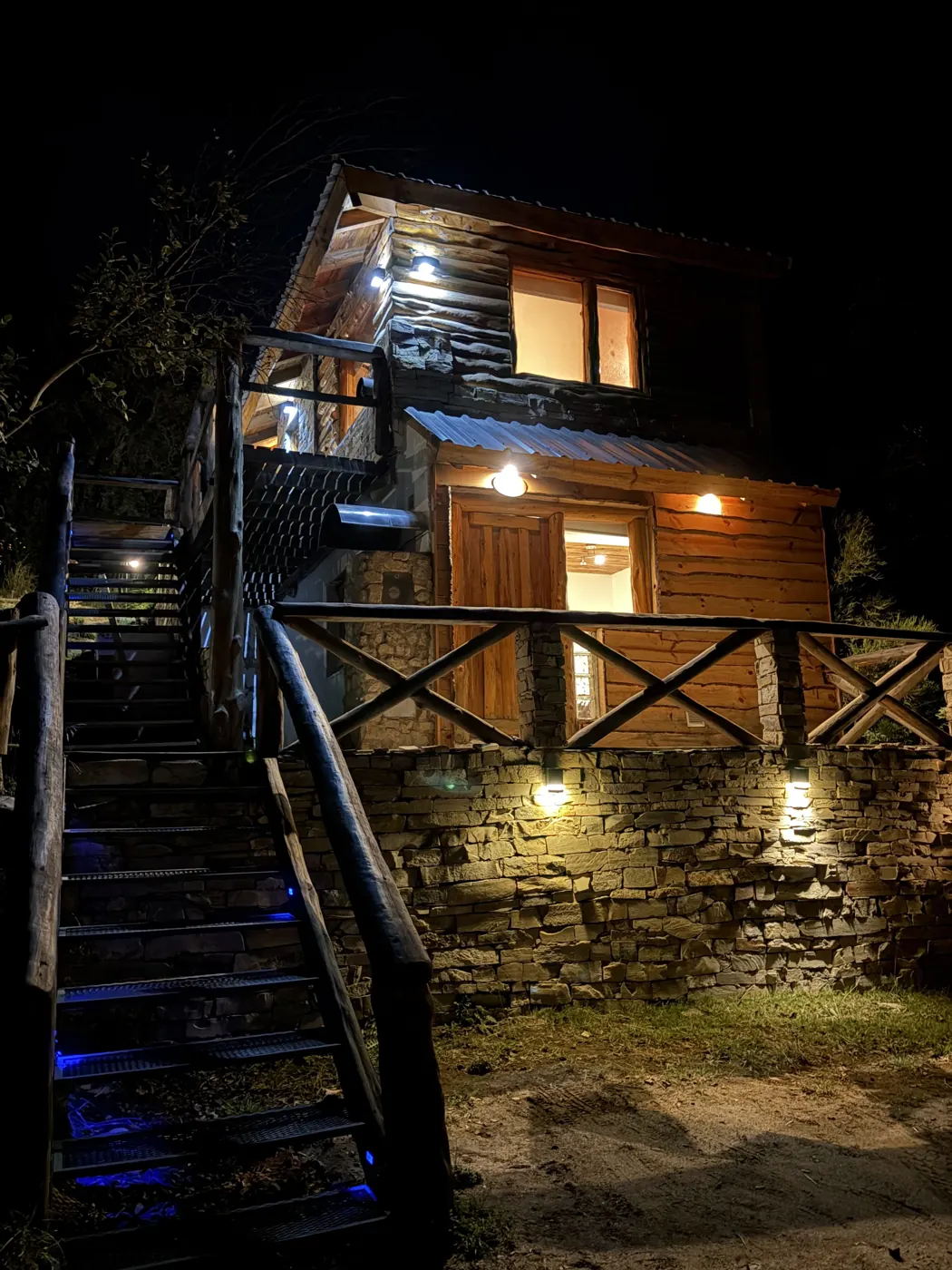 Cabaña Amulen de noche con luces cálidas y escalera de acceso en Villa Pehuenia
