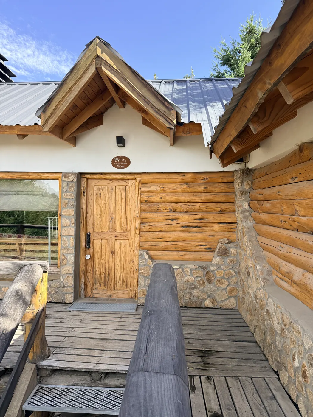 Entrada de la cabaña Lihuen con puerta de madera y piedra