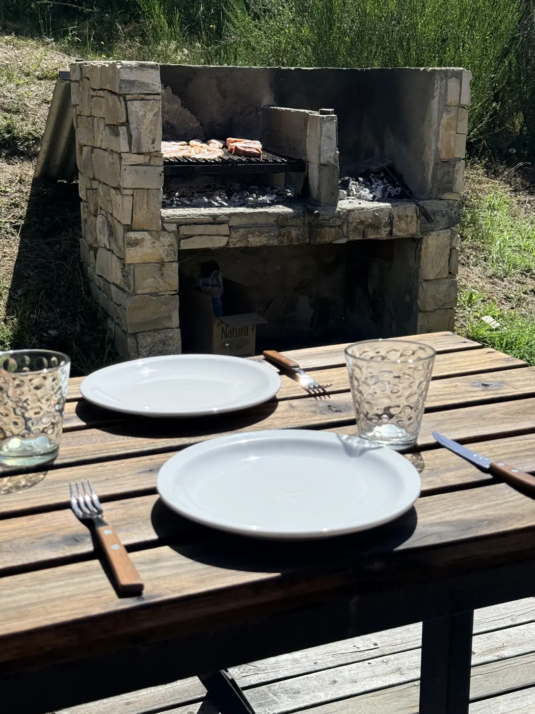 Asador de piedra y mesa de madera junto a la cabaña Quimey